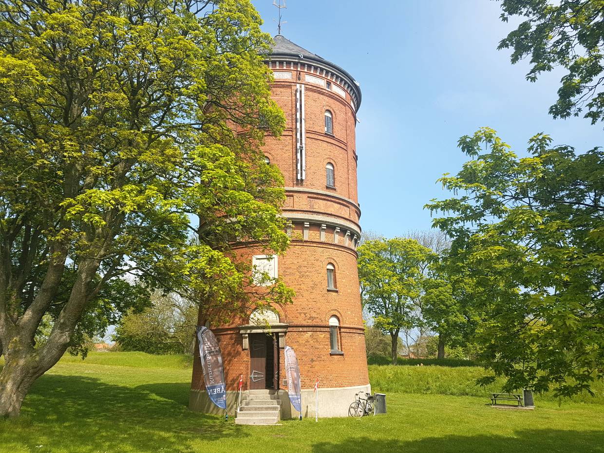 Roter Backsteinturm zwischen Laubbäumen