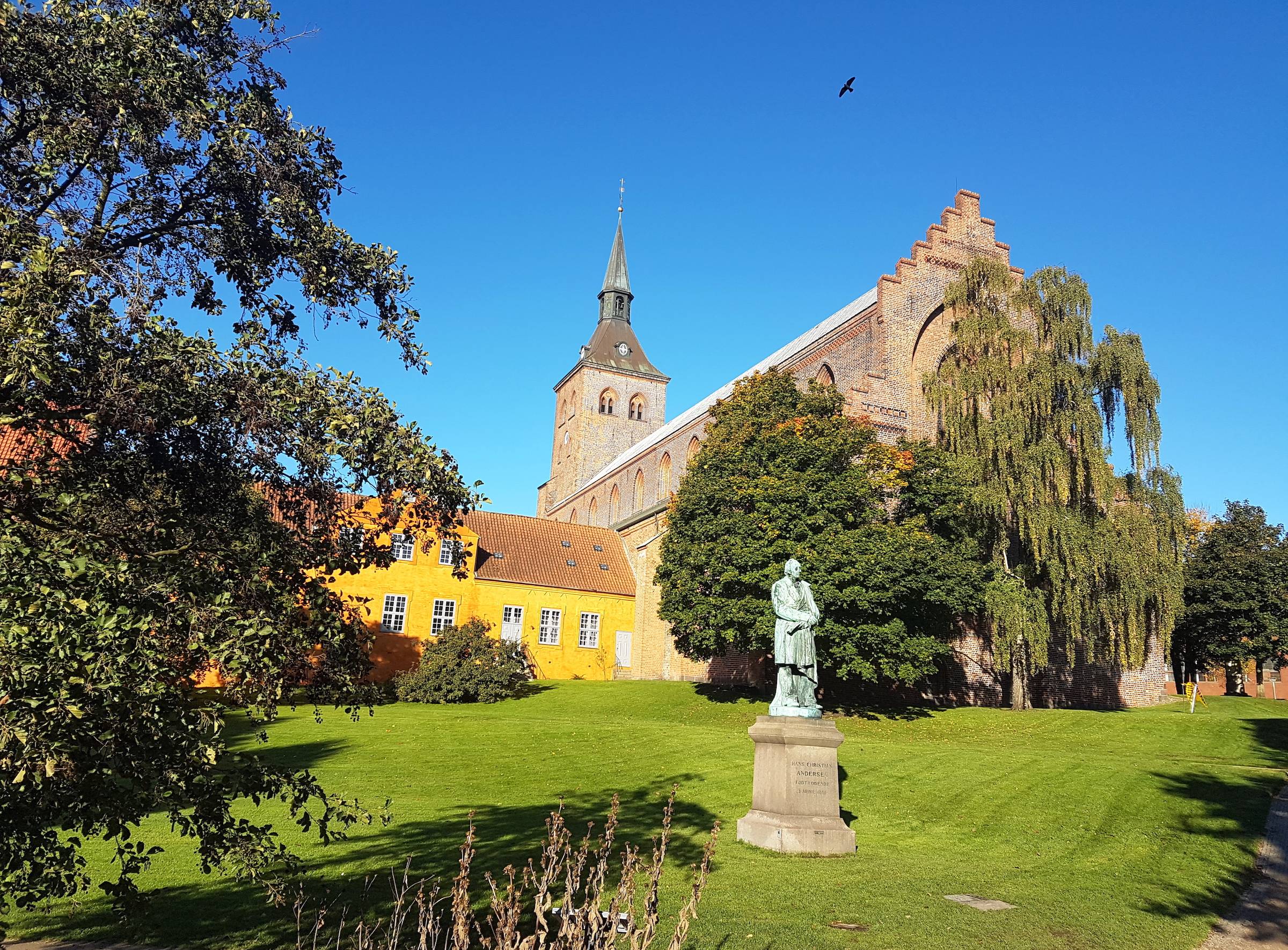Blick auf den Odense Dom vom Park aus mit einem Denkmal für Hans Christian Andersen im Vordergrund