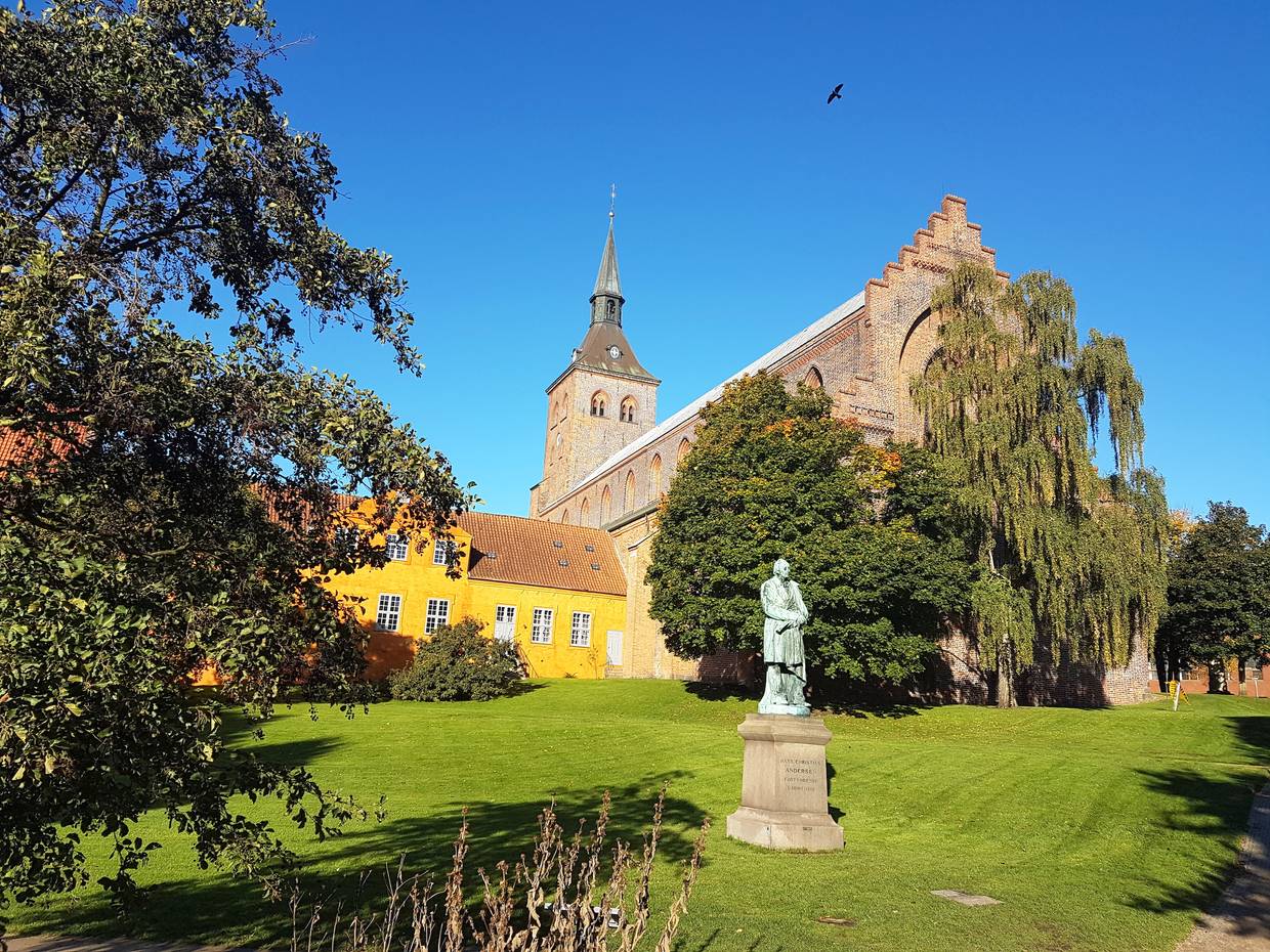 Blick auf den Odense Dom vom Park aus mit einem Denkmal für Hans Christian Andersen im Vordergrund