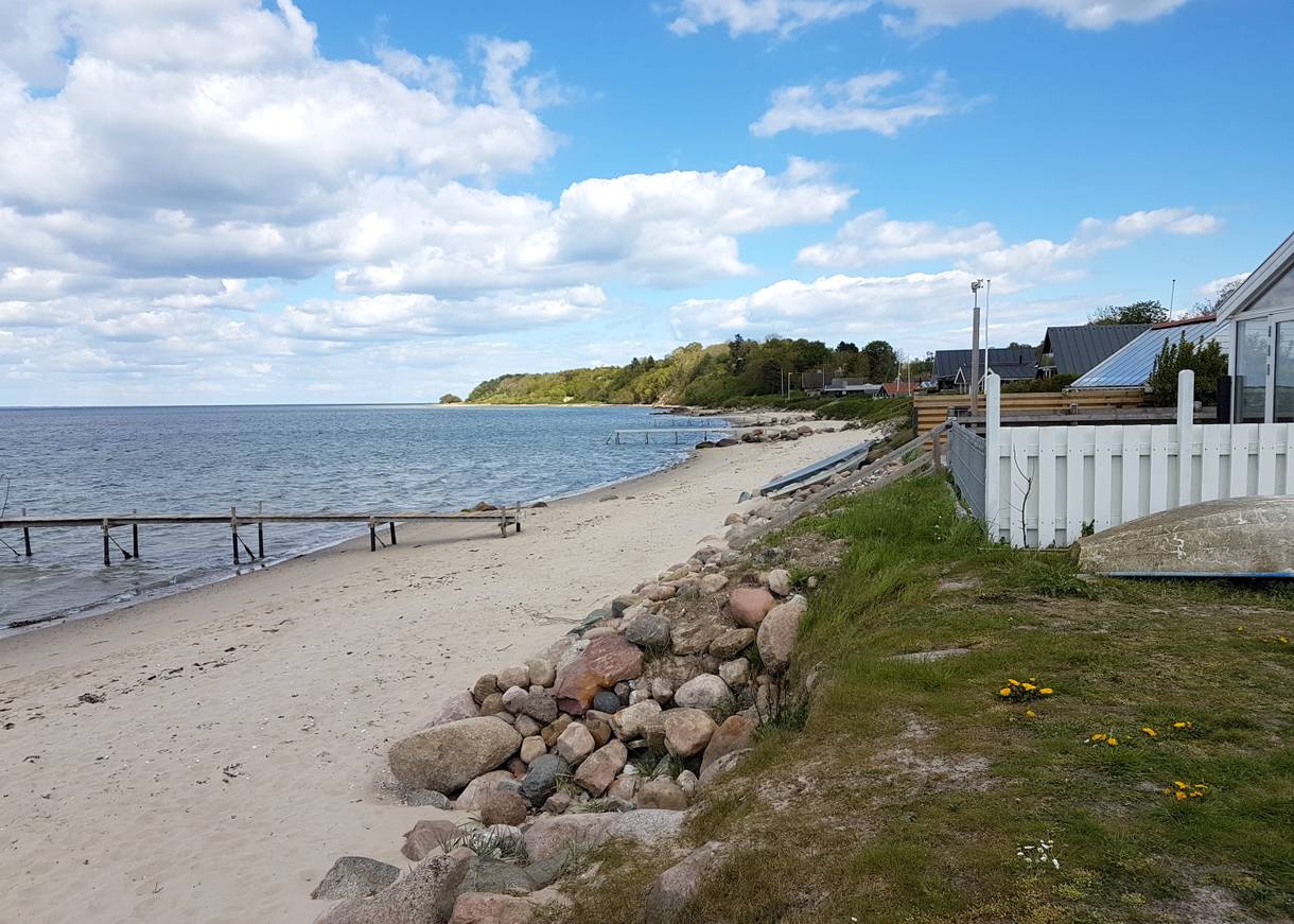 Sandstrand unterhalb einer Ferienhaussiedlung mit Trppen zum Strand