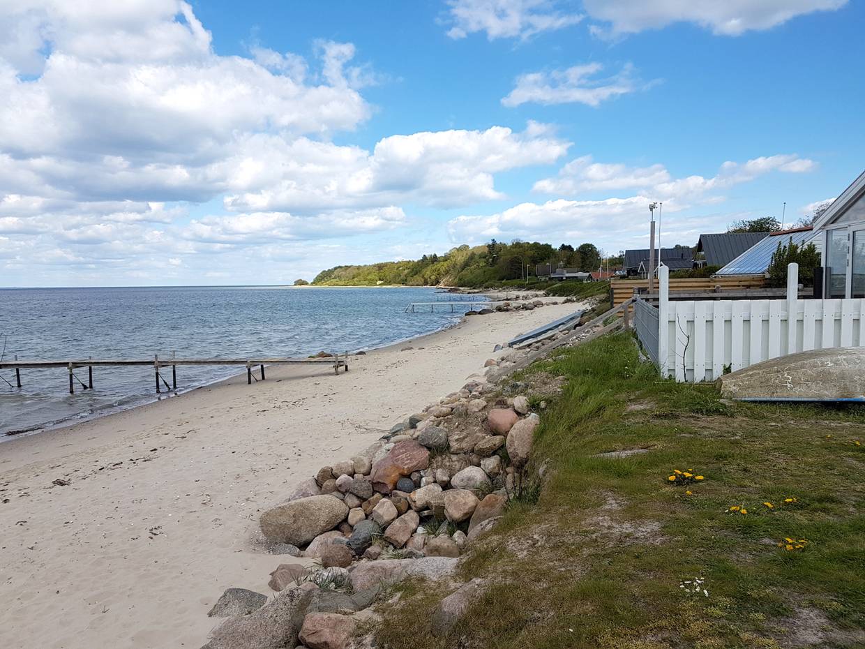 Sandstrand unterhalb einer Ferienhaussiedlung mit Trppen zum Strand
