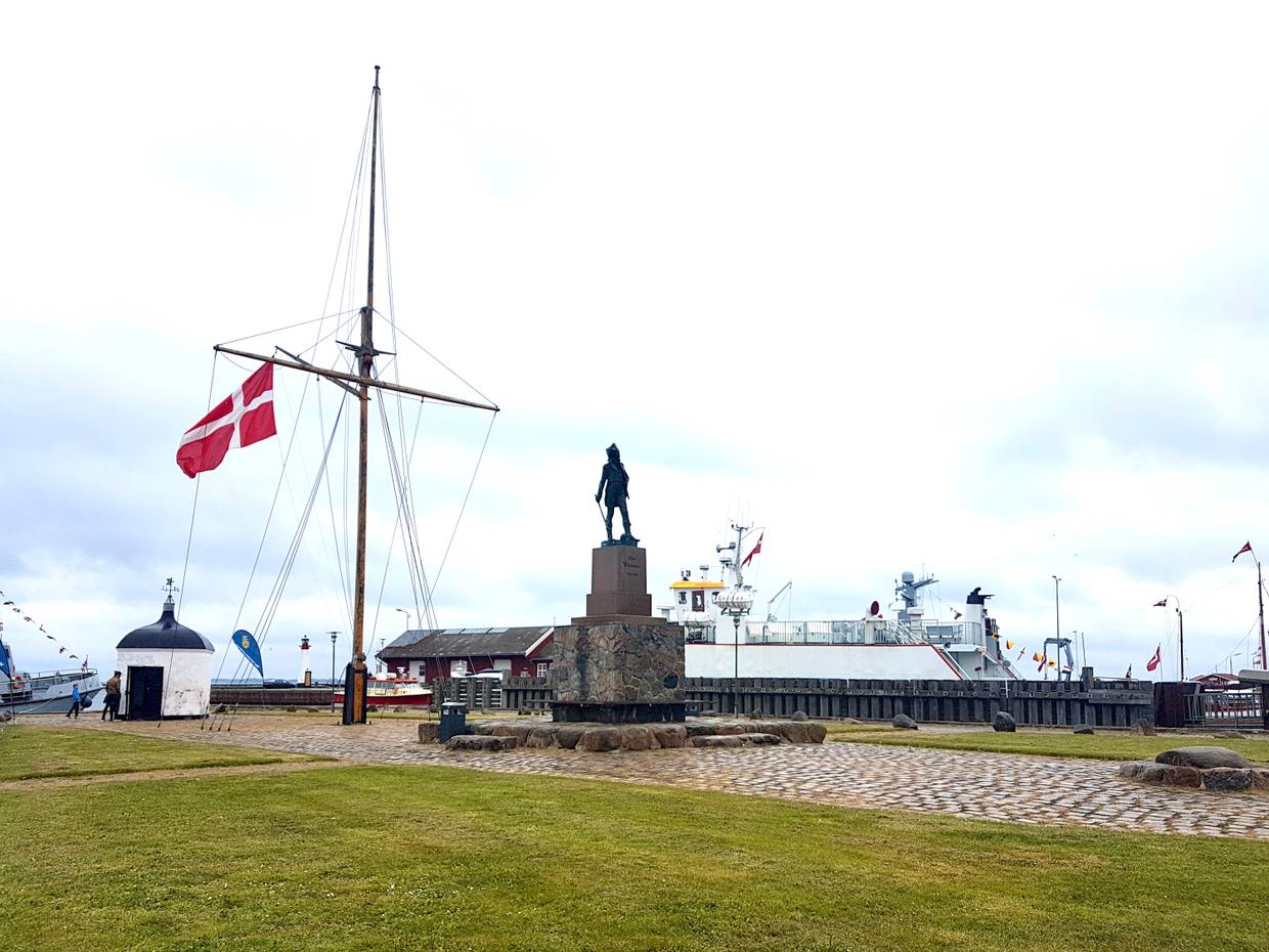Blick auf einen Kreisel mit einem Denkmal, dahinter eine weiße Fähre