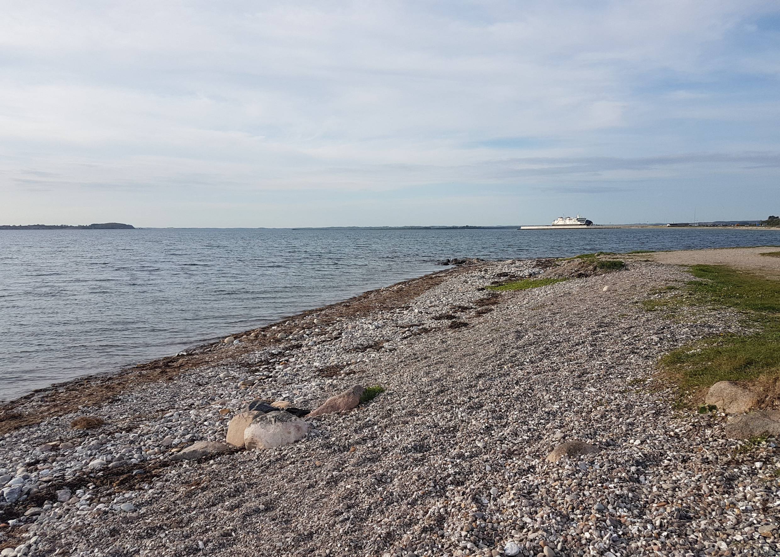 Steiniger Strand, im Hintergrund ein Fähranleger
