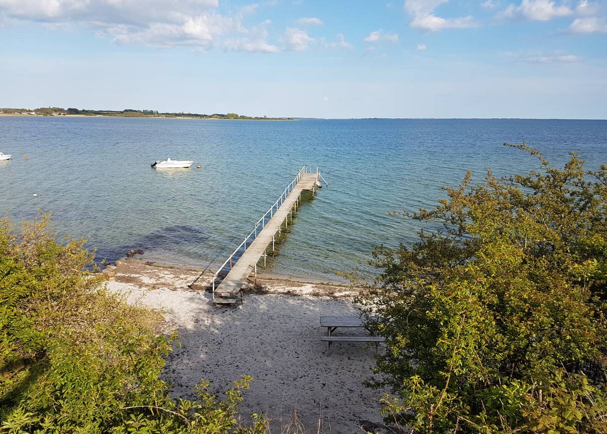 Blick auf einen kleinen Sandstrand mit Badesteg