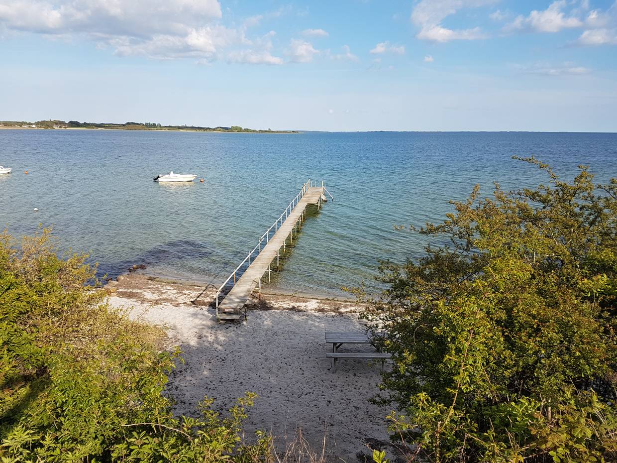 Blick auf einen kleinen Sandstrand mit Badesteg