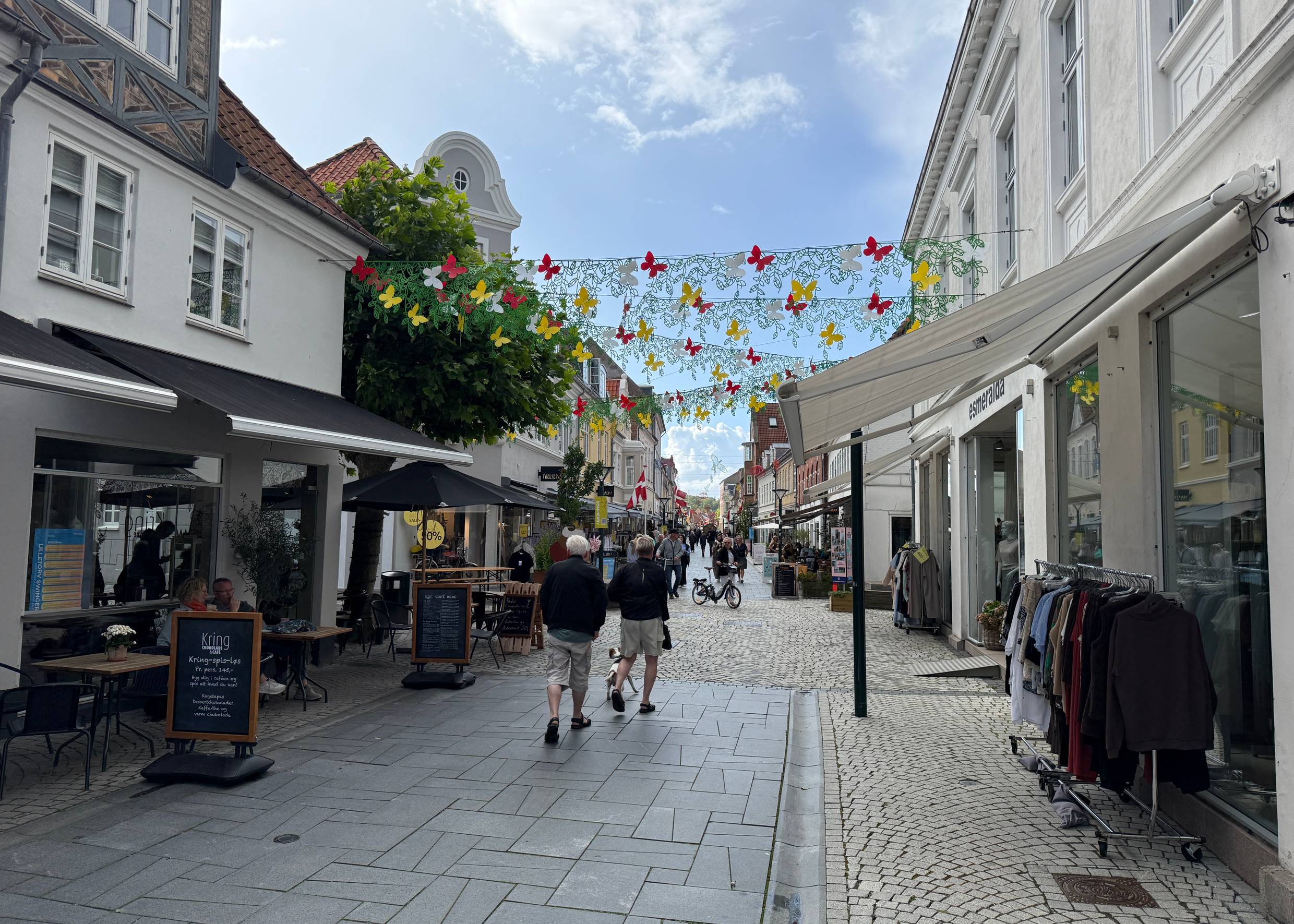 Einkaufsstraße mit kleinen Geschäften und Kleiderständer davor