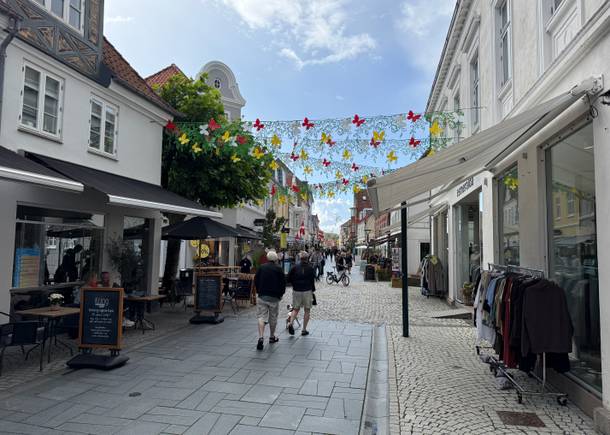 Einkaufsstraße mit kleinen Geschäften und Kleiderständer davor