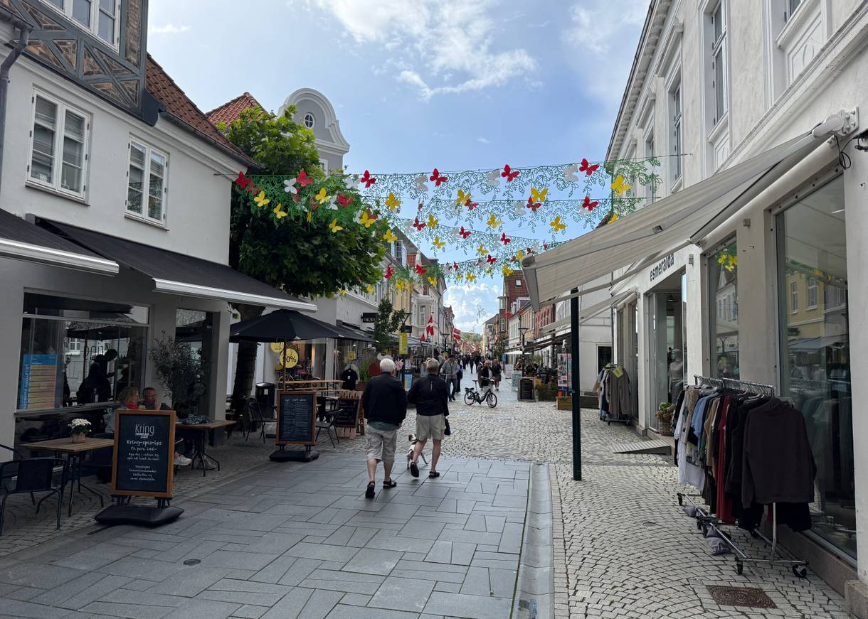 Einkaufsstraße mit kleinen Geschäften und Kleiderständer davor