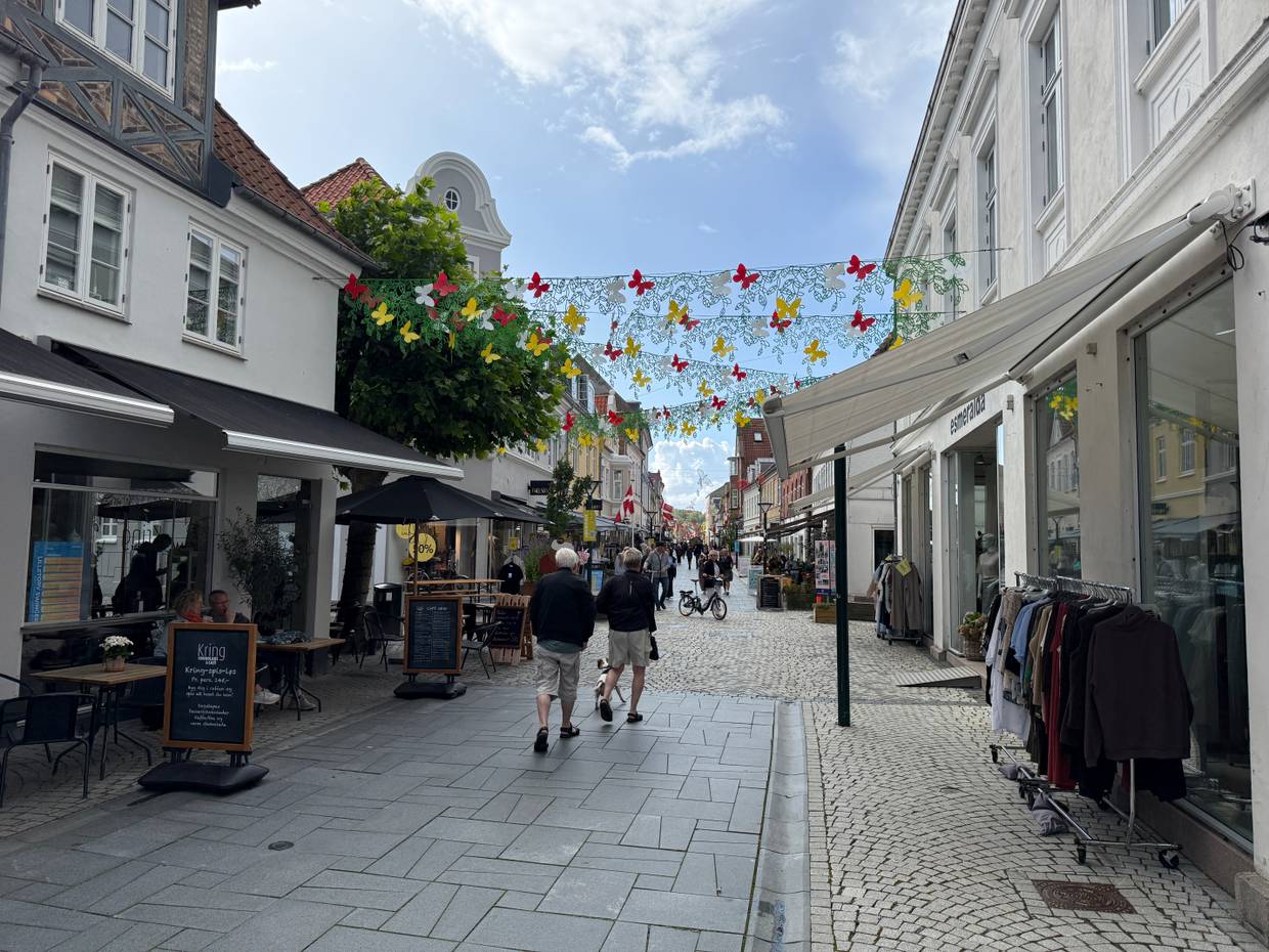 Einkaufsstraße mit kleinen Geschäften und Kleiderständer davor