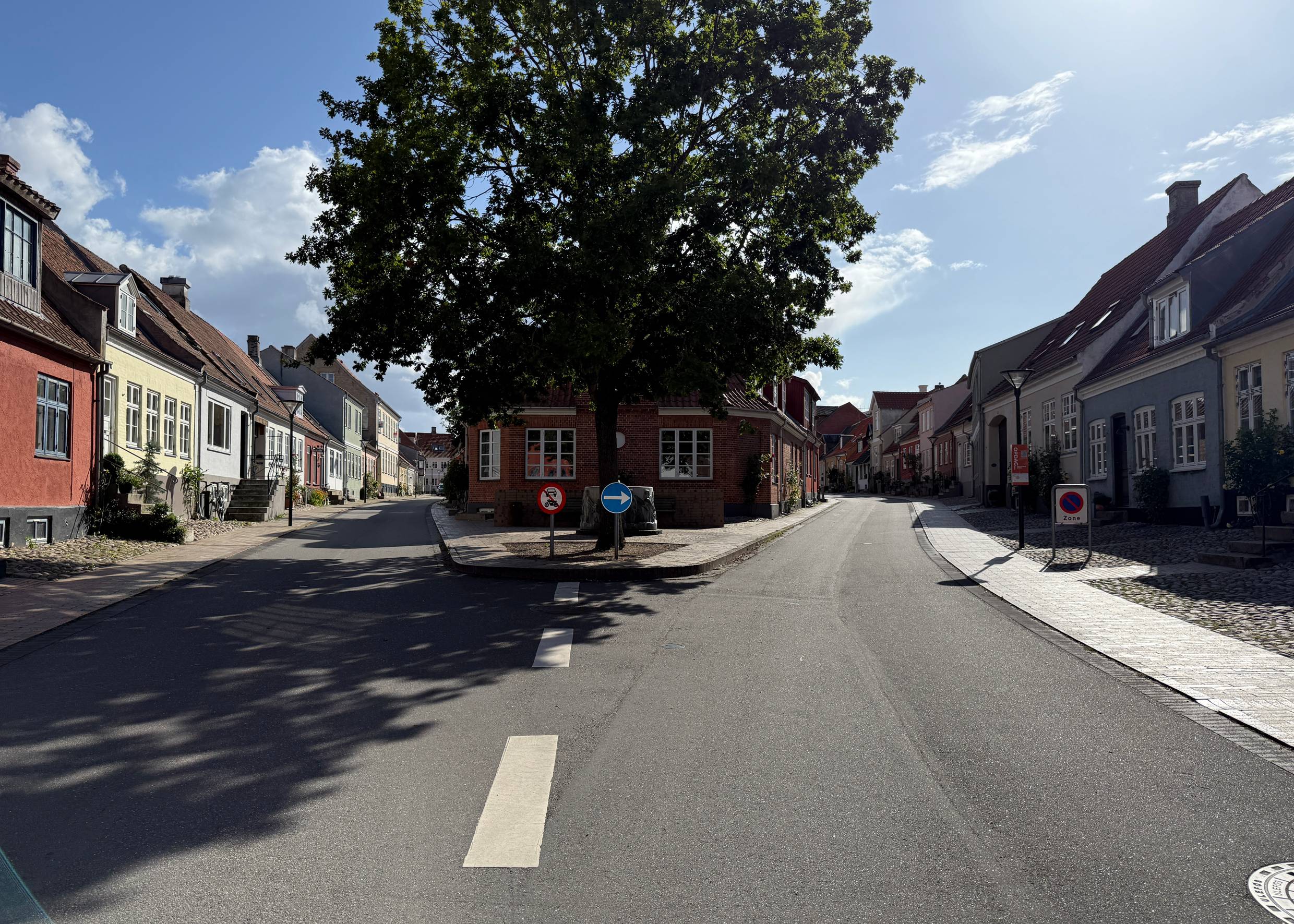 Blick durch zwei kleine Gassen durchtrennt von einem kleinen Platz mit Baum und Brunnen