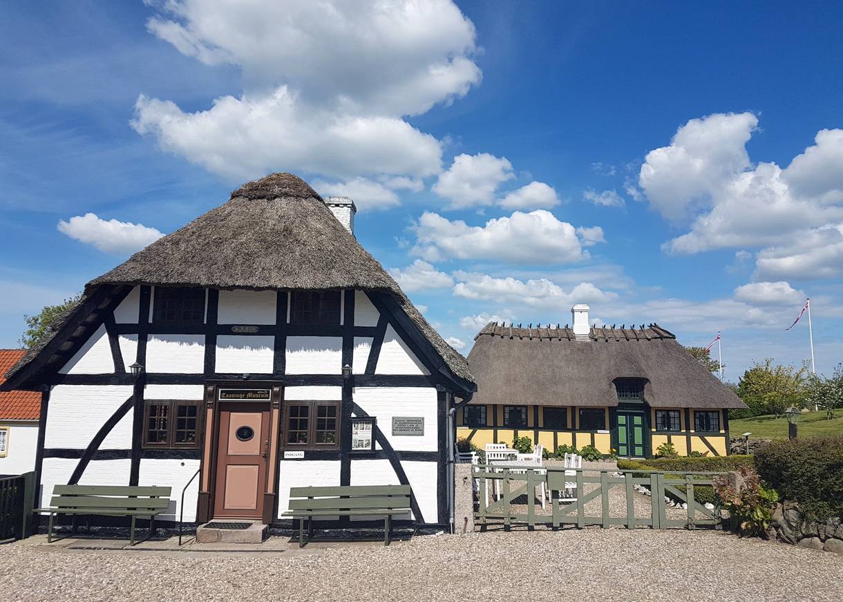 Weißes Fachwerkhaus mit einer Bank im Hof