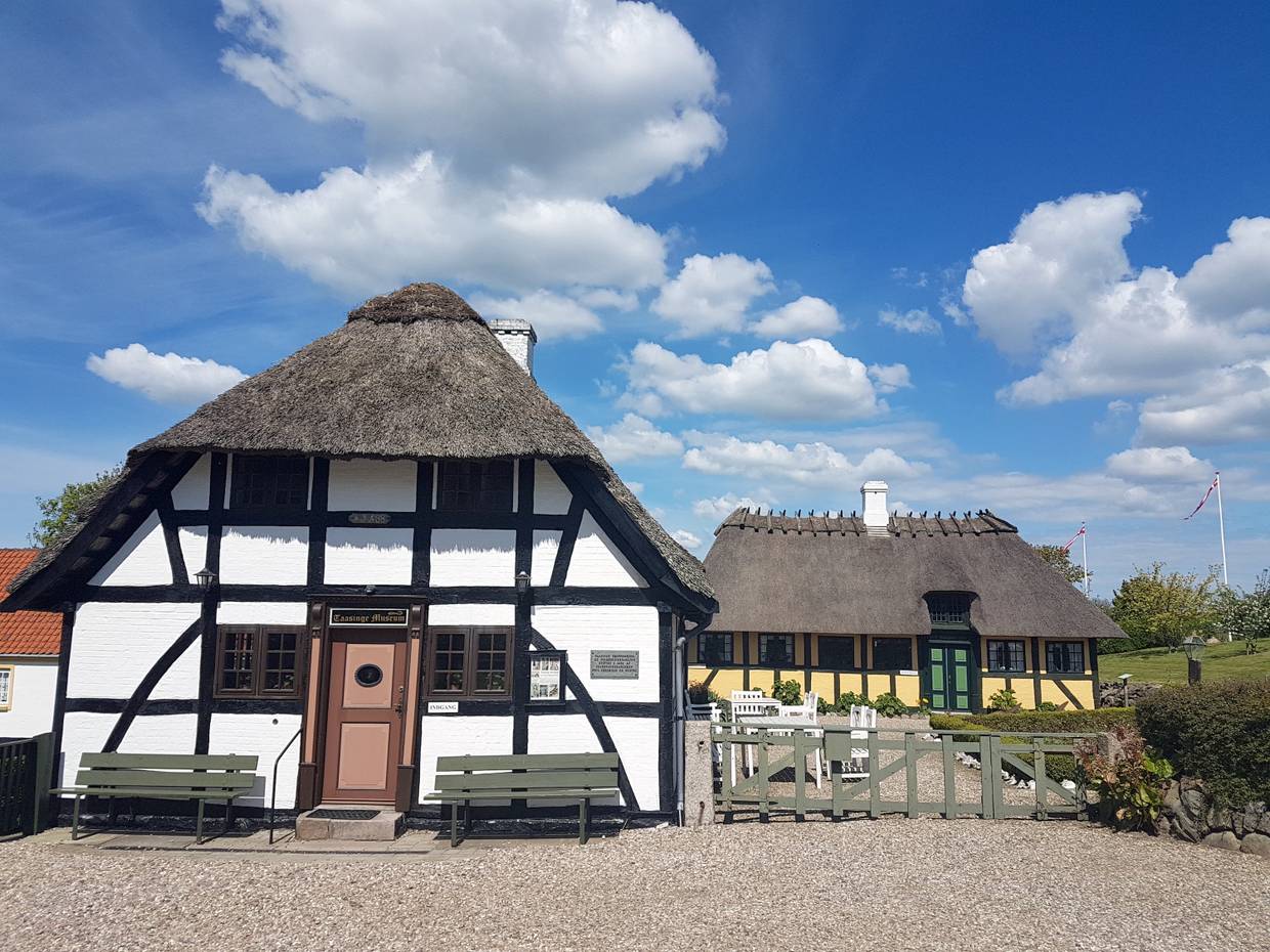 Weißes Fachwerkhaus mit einer Bank im Hof