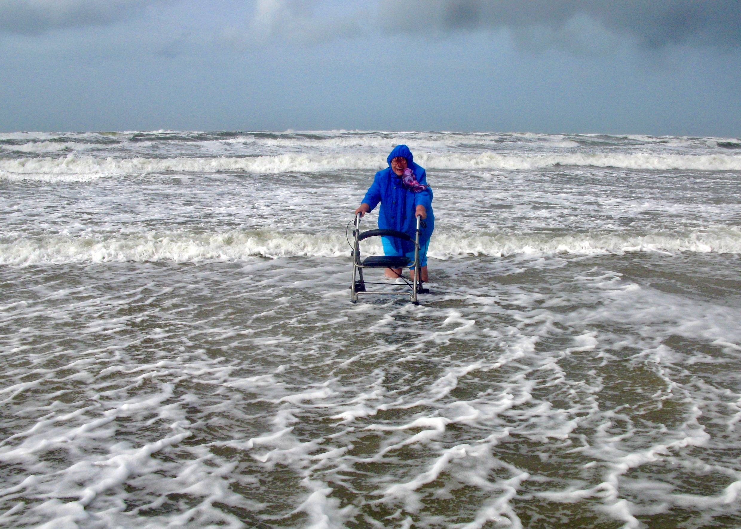 Frau mit Rollator und Windjacke in den Wellen