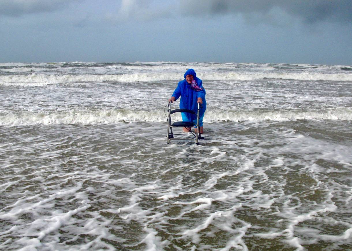 Frau mit Rollator und Windjacke in den Wellen