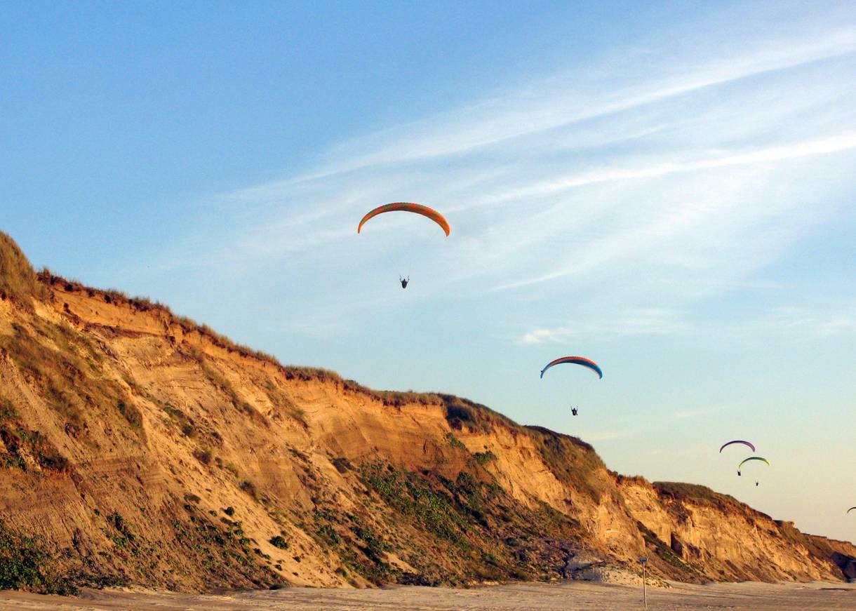 Paraglider über einer sandigen Steilküste