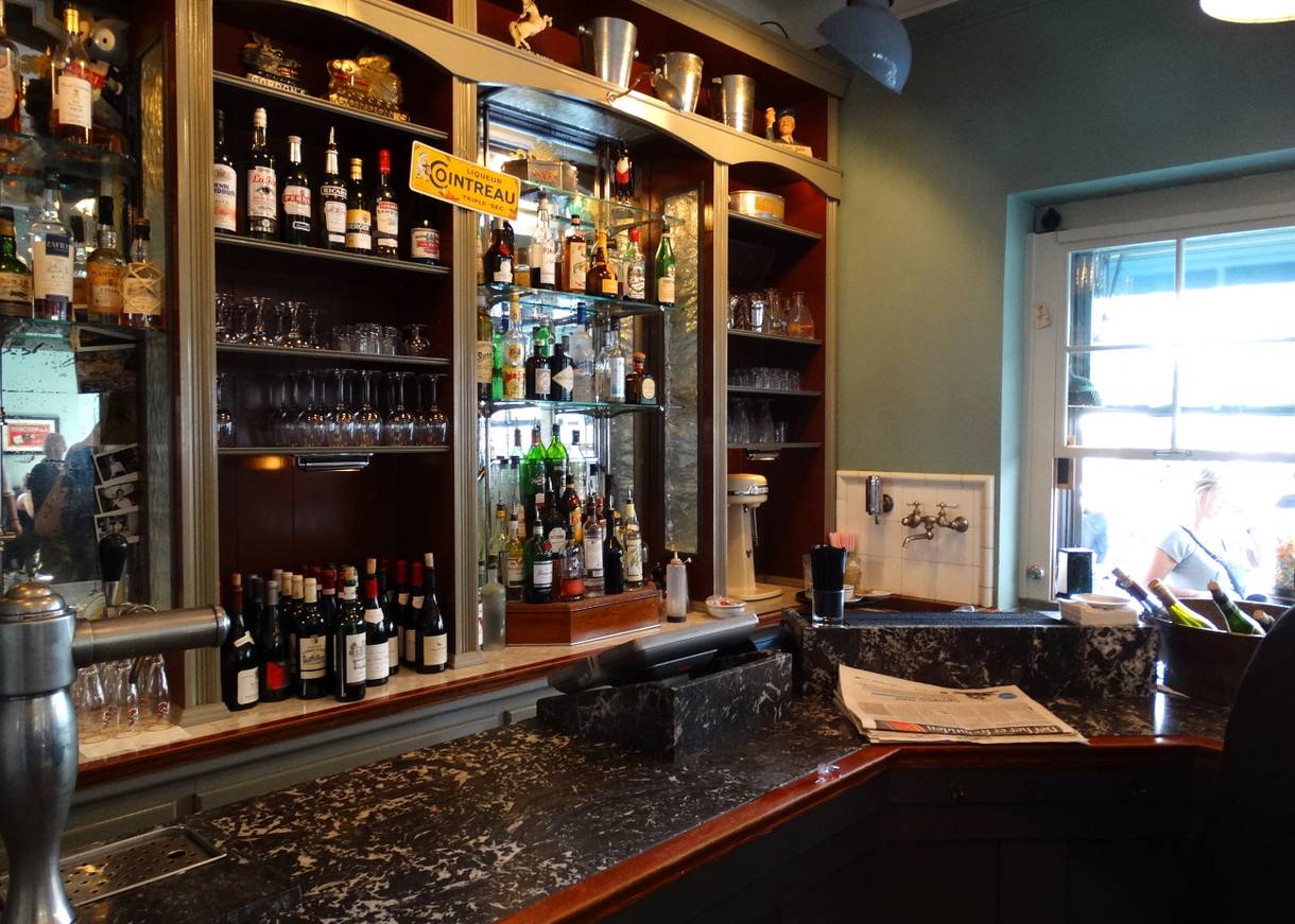 Ein Schrank mit Flaschen und Gläsern in einer französisch anmutenden Bar