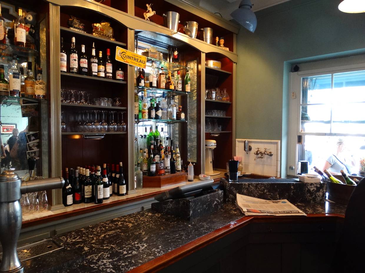 Ein Schrank mit Flaschen und Gläsern in einer französisch anmutenden Bar