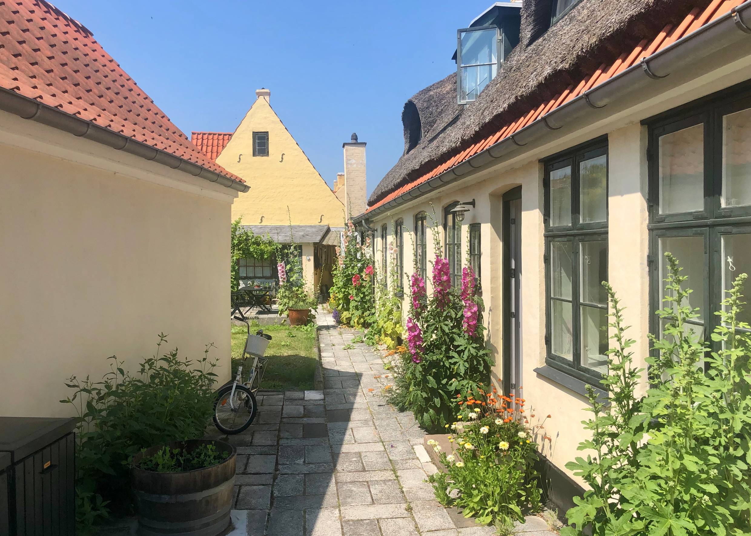 Hof zwischen gelben Wohnhäusern mit vielen Blumen geschmückt
