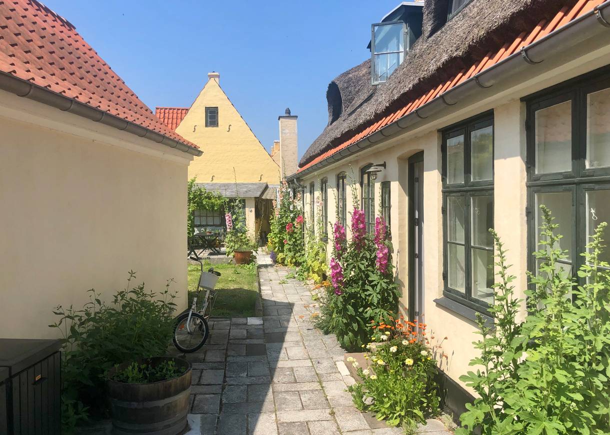 Hof zwischen gelben Wohnhäusern mit vielen Blumen geschmückt