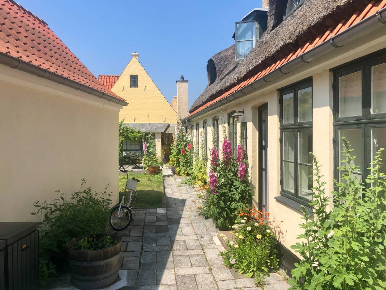 Hof zwischen gelben Wohnhäusern mit vielen Blumen geschmückt