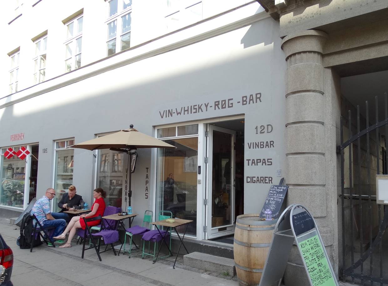 Gäste auf Klappstühlen auf dem Bürgersteig vor einer Bar