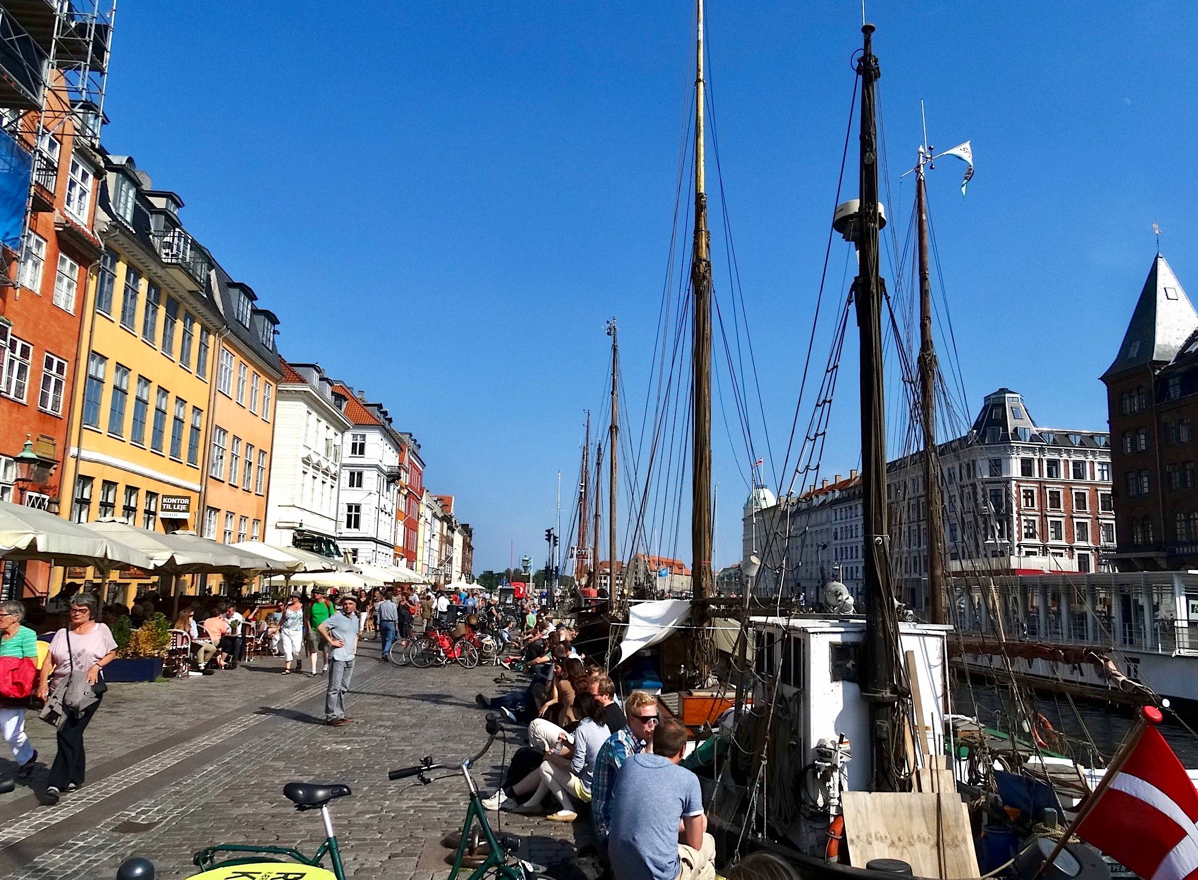 Viele Menschen zwischen Segelschiffen und bunten Häusern