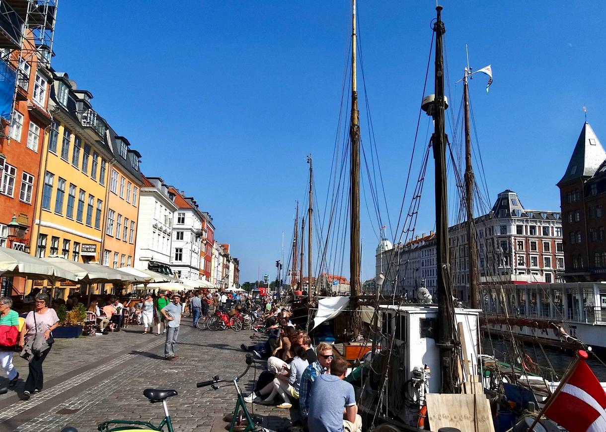 Viele Menschen zwischen Segelschiffen und bunten Häusern