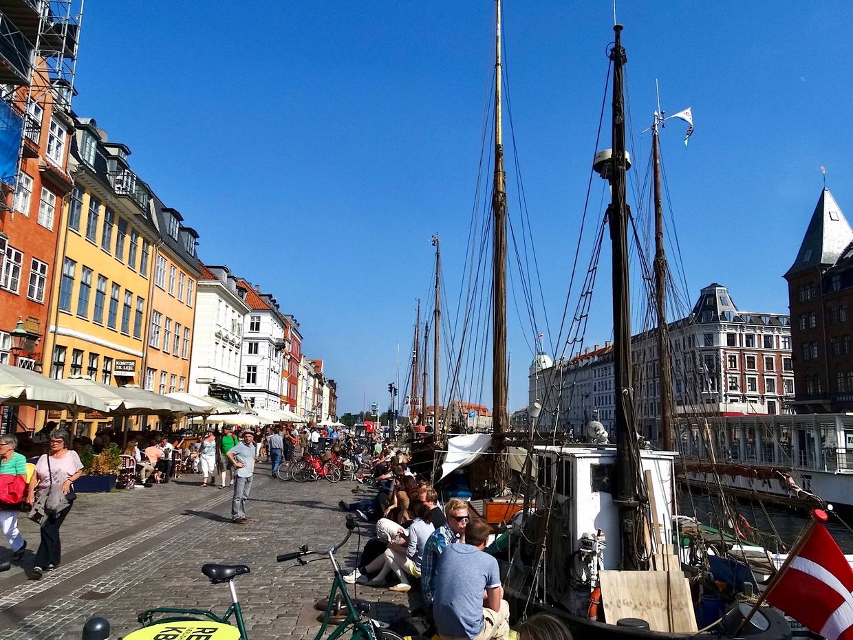 Viele Menschen zwischen Segelschiffen und bunten Häusern