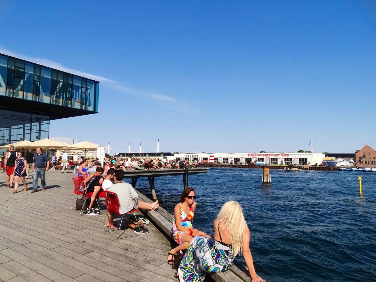 Menschen in Sommerkleidung an der Hafenkante vor dem Schauspielhaus