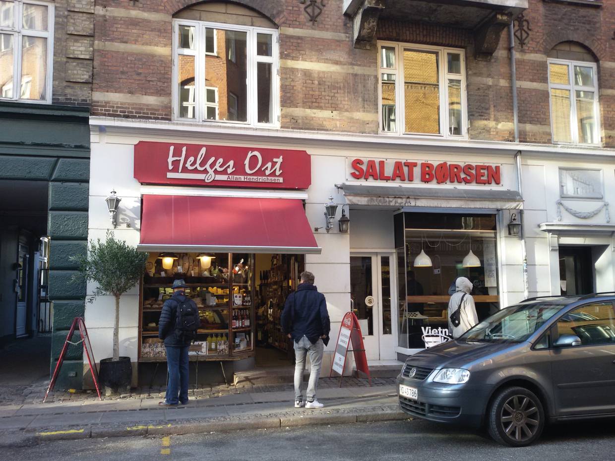 Zwei kleine Lebensmittelgeschäfte mit rotem Schriftzug, davor Kunden