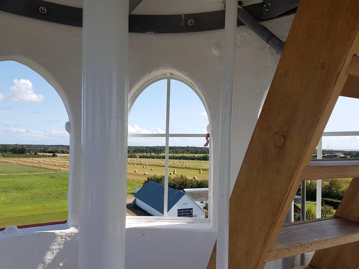 Blick durch bogenförmige Fenster über Stoppelfelder und Wald