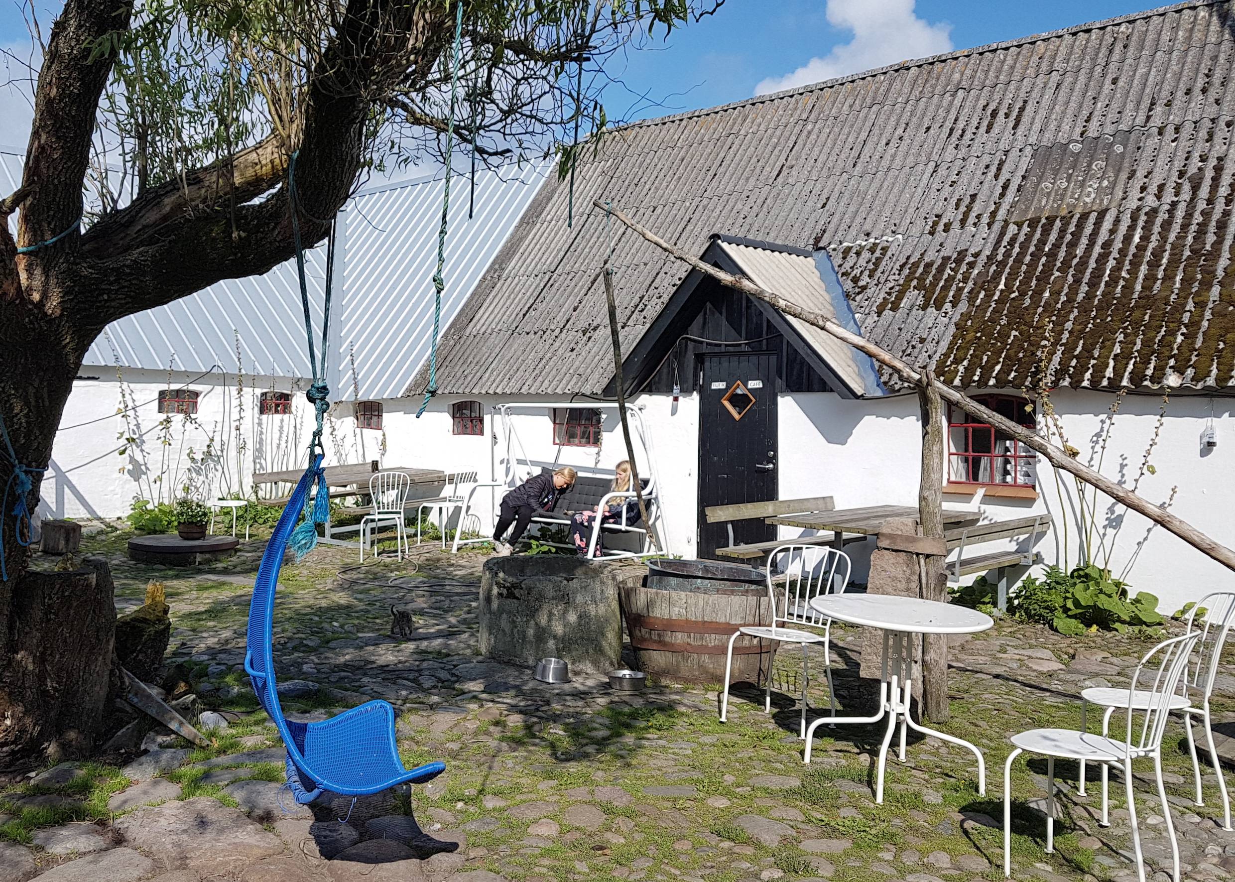 Innenhof des Cafés mit Kopfsteinpflaster, urigen Möbeln und zwei Kindern im hinteren Bereich