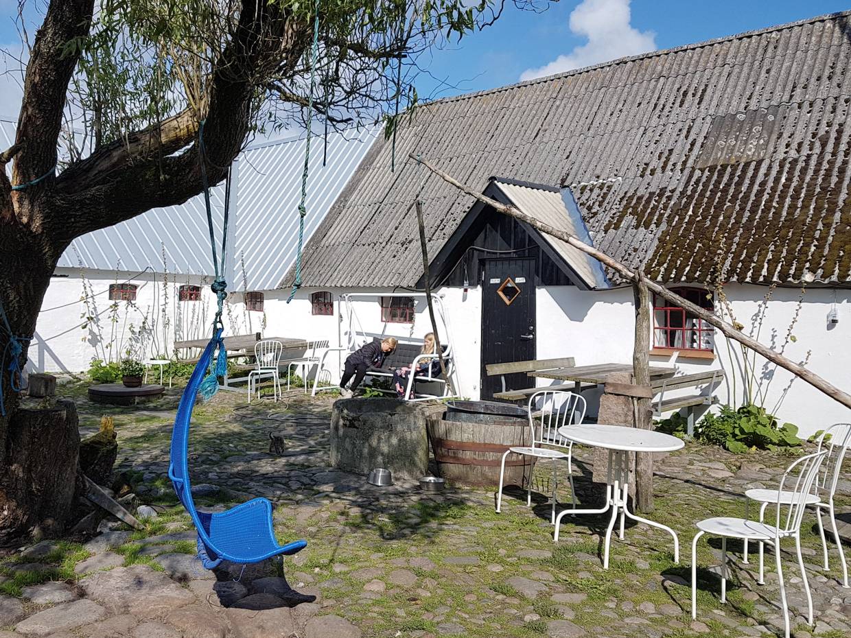 Innenhof des Cafés mit Kopfsteinpflaster, urigen Möbeln und zwei Kindern im hinteren Bereich