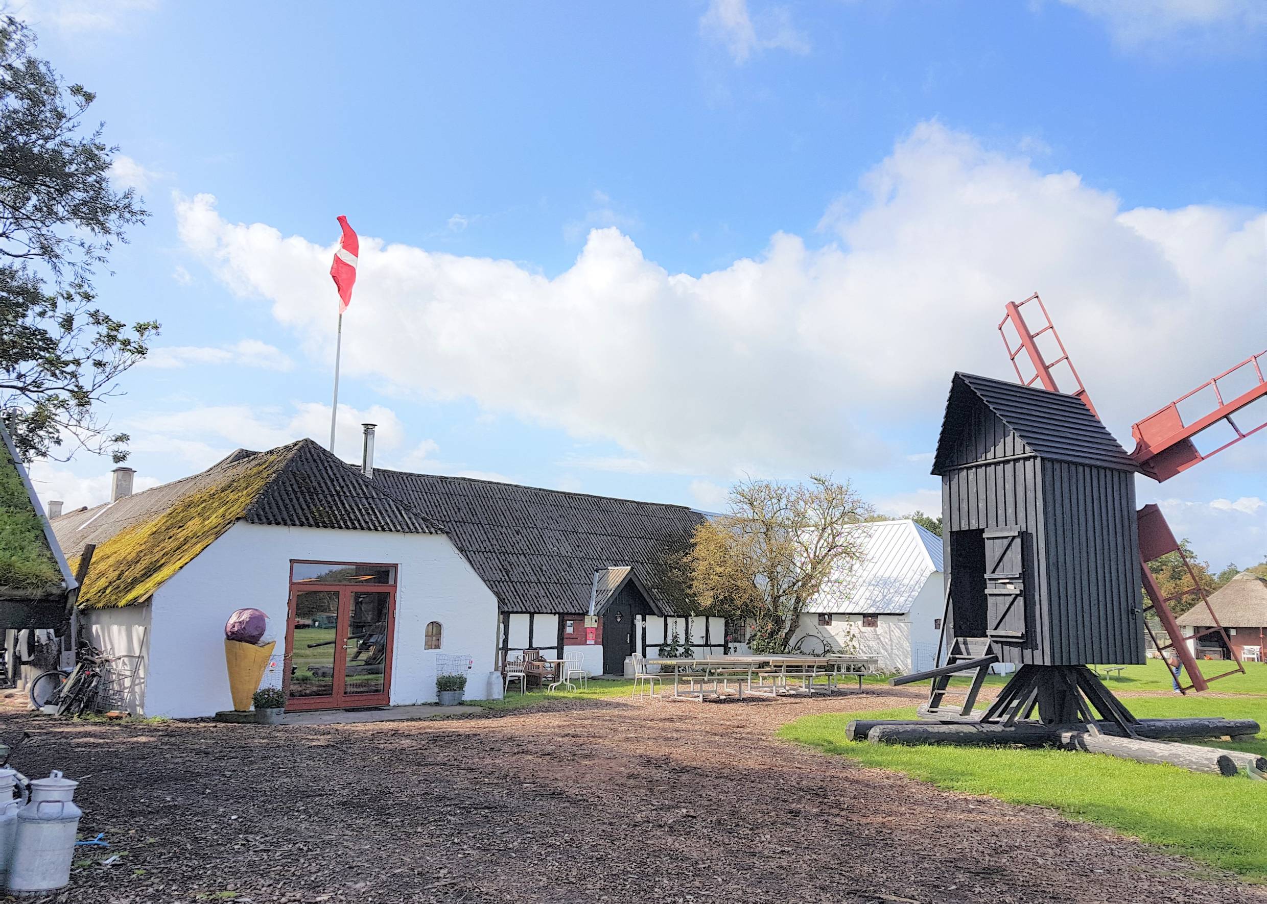 Weißer Bauernhof, davor eine kleine Windmühle