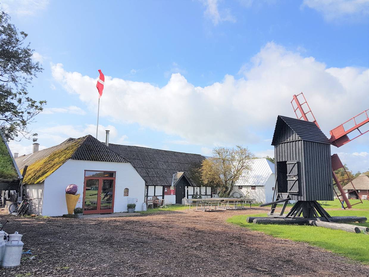 Weißer Bauernhof, davor eine kleine Windmühle