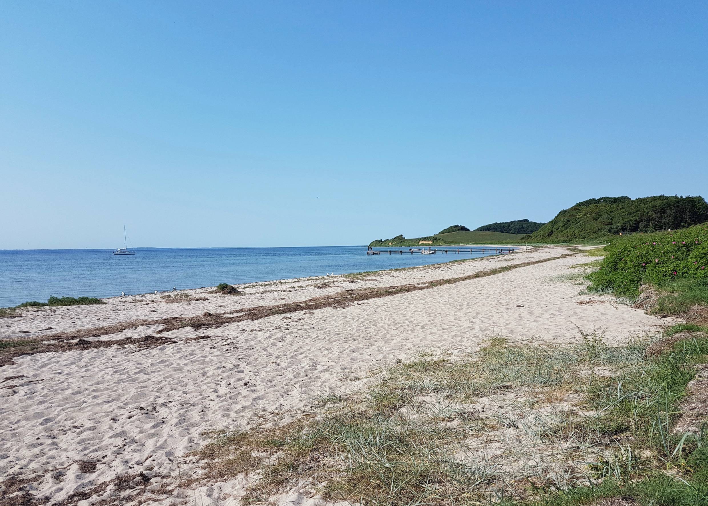 Blick über einen langen Sandstrand bei windstillem Wetter