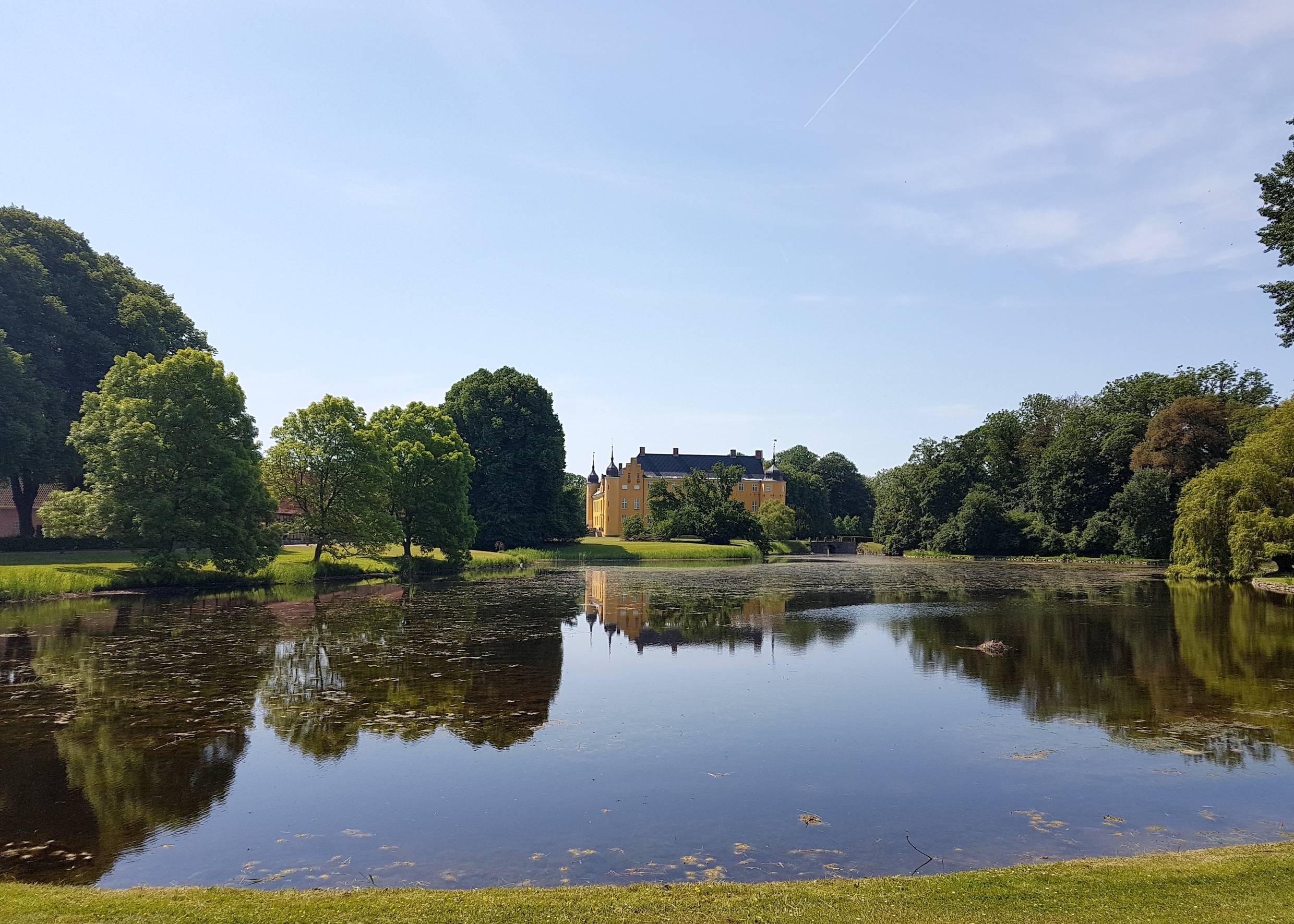 Blick auf ein gelbes Schloss hinter einem blauen See