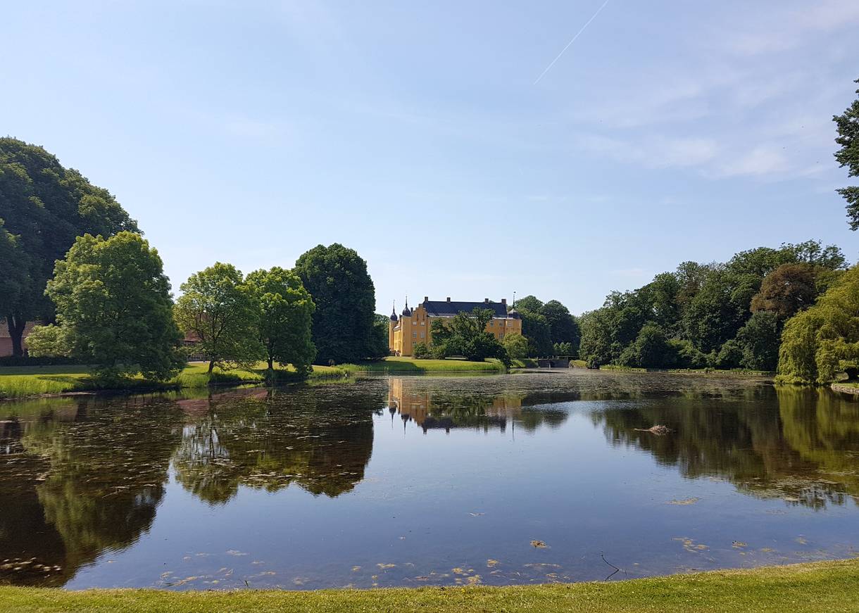 Blick auf ein gelbes Schloss hinter einem blauen See