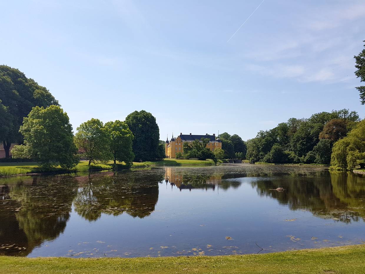 Blick auf ein gelbes Schloss hinter einem blauen See