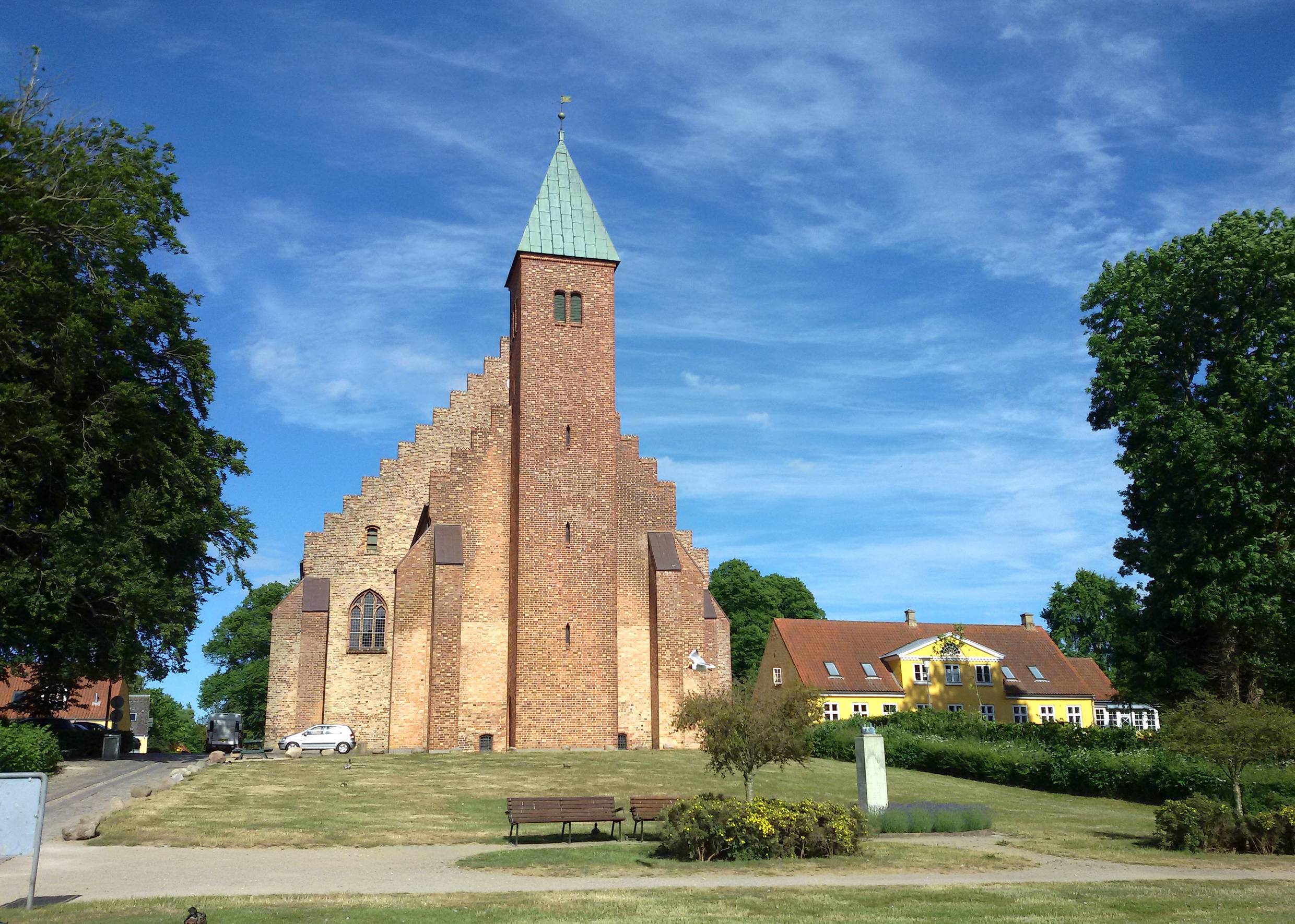 Sehr große Backsteinkirche mit ungewöhnlicher Form, davor eine Parkanlage