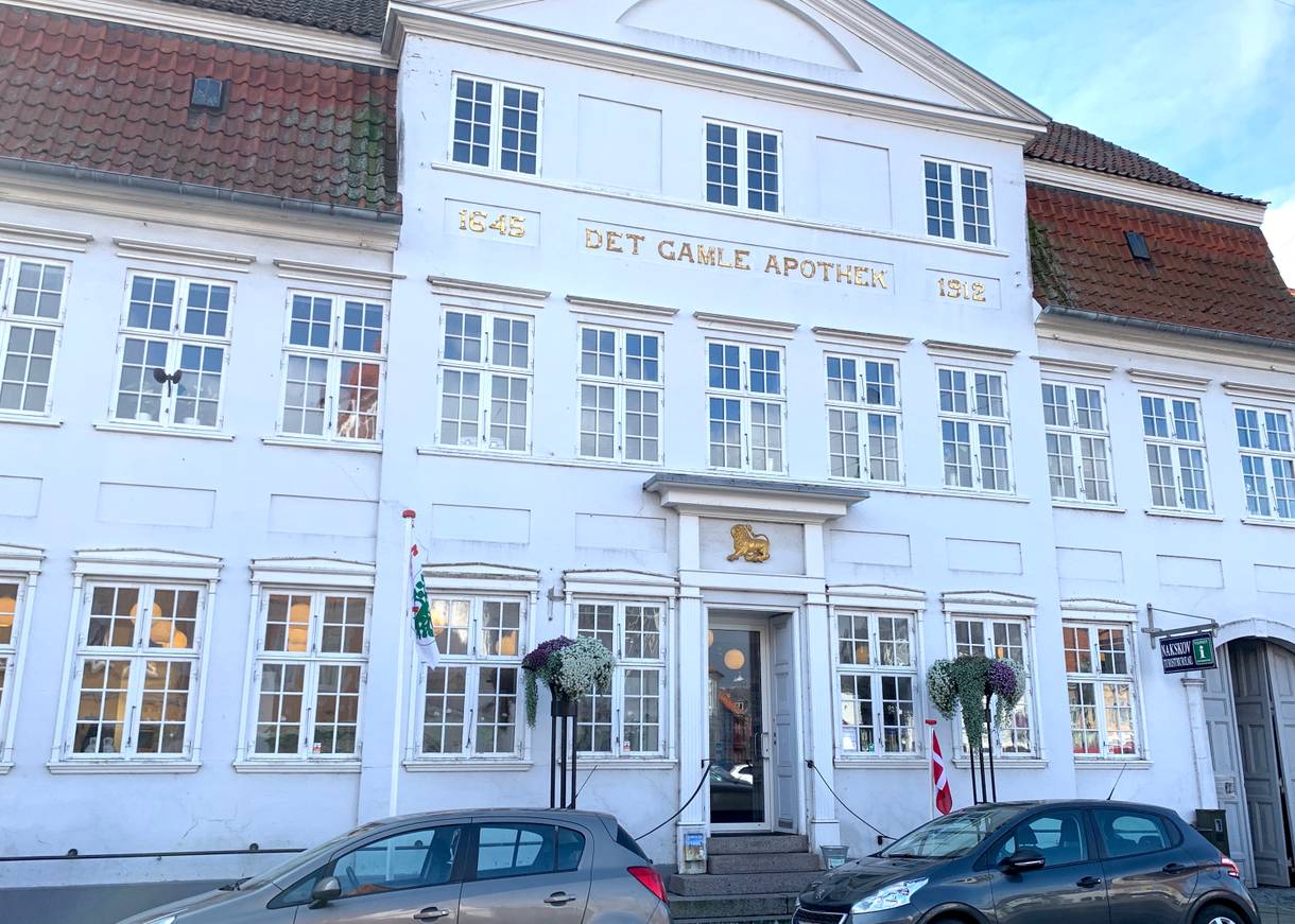 Weißes Haus mit goldener Aufschrift Det gamle Apothek