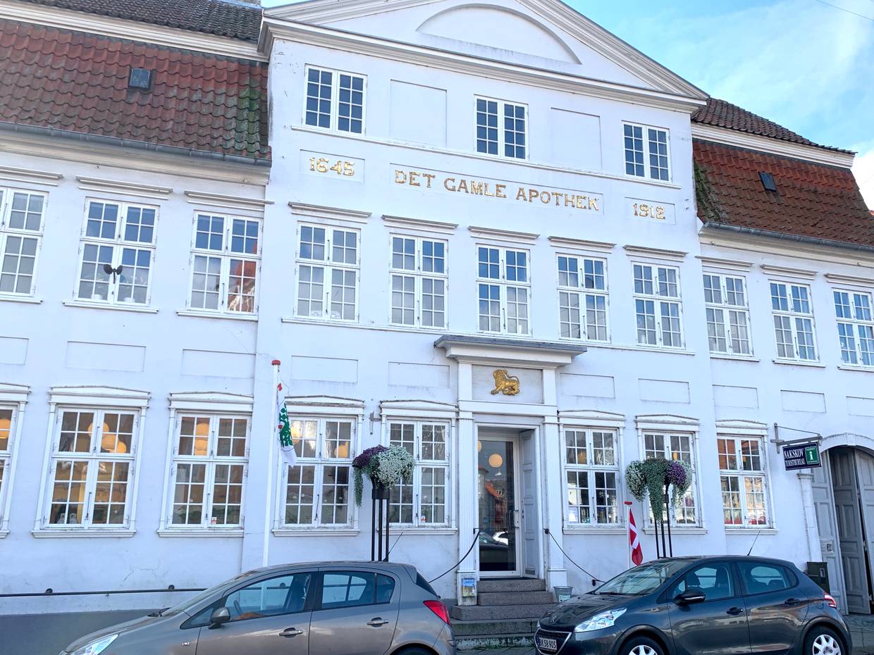 Weißes Haus mit goldener Aufschrift Det gamle Apothek
