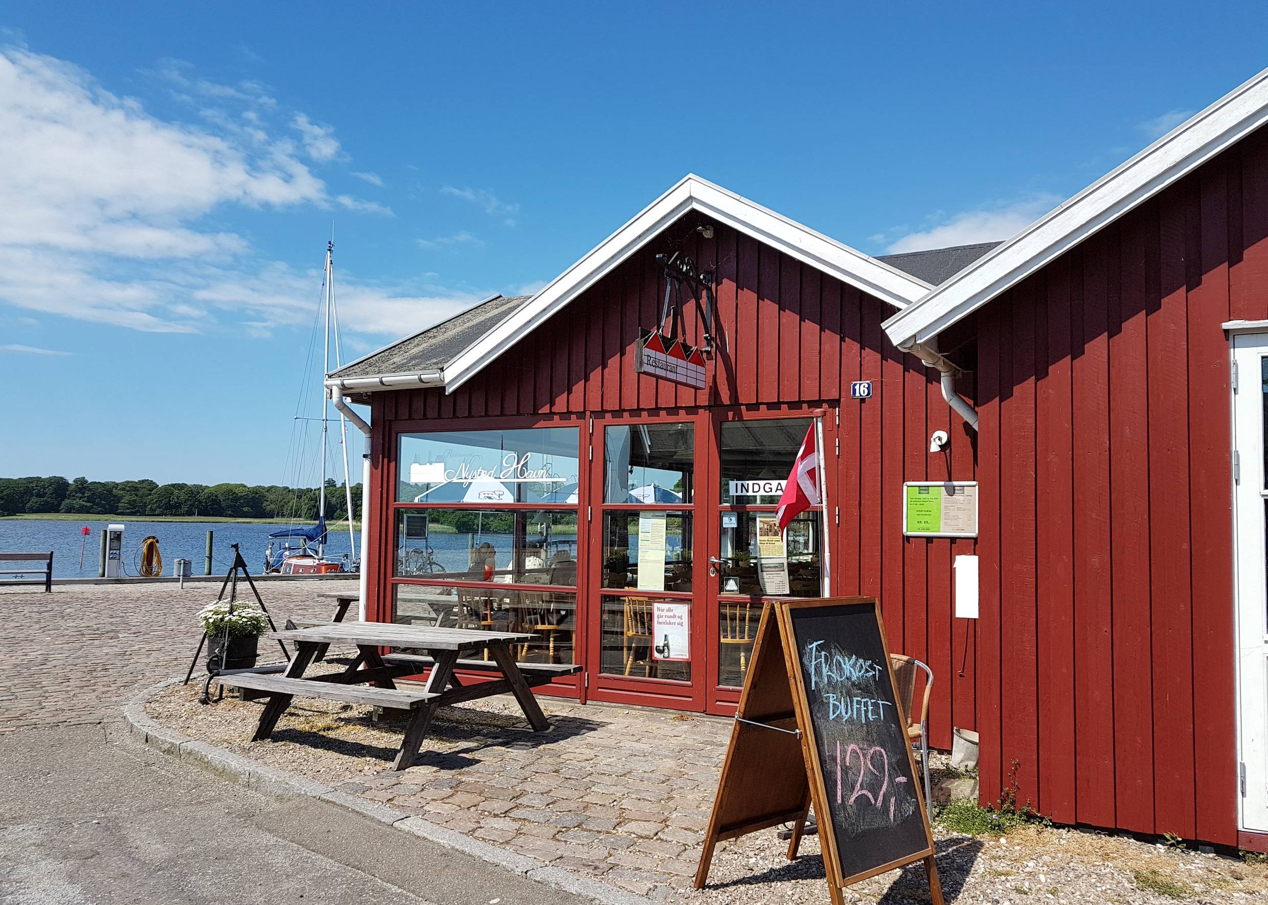 Rotes Holzhaus mit Picknickbänken am Hafen