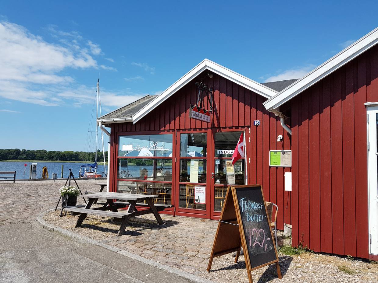 Rotes Holzhaus mit Picknickbänken am Hafen