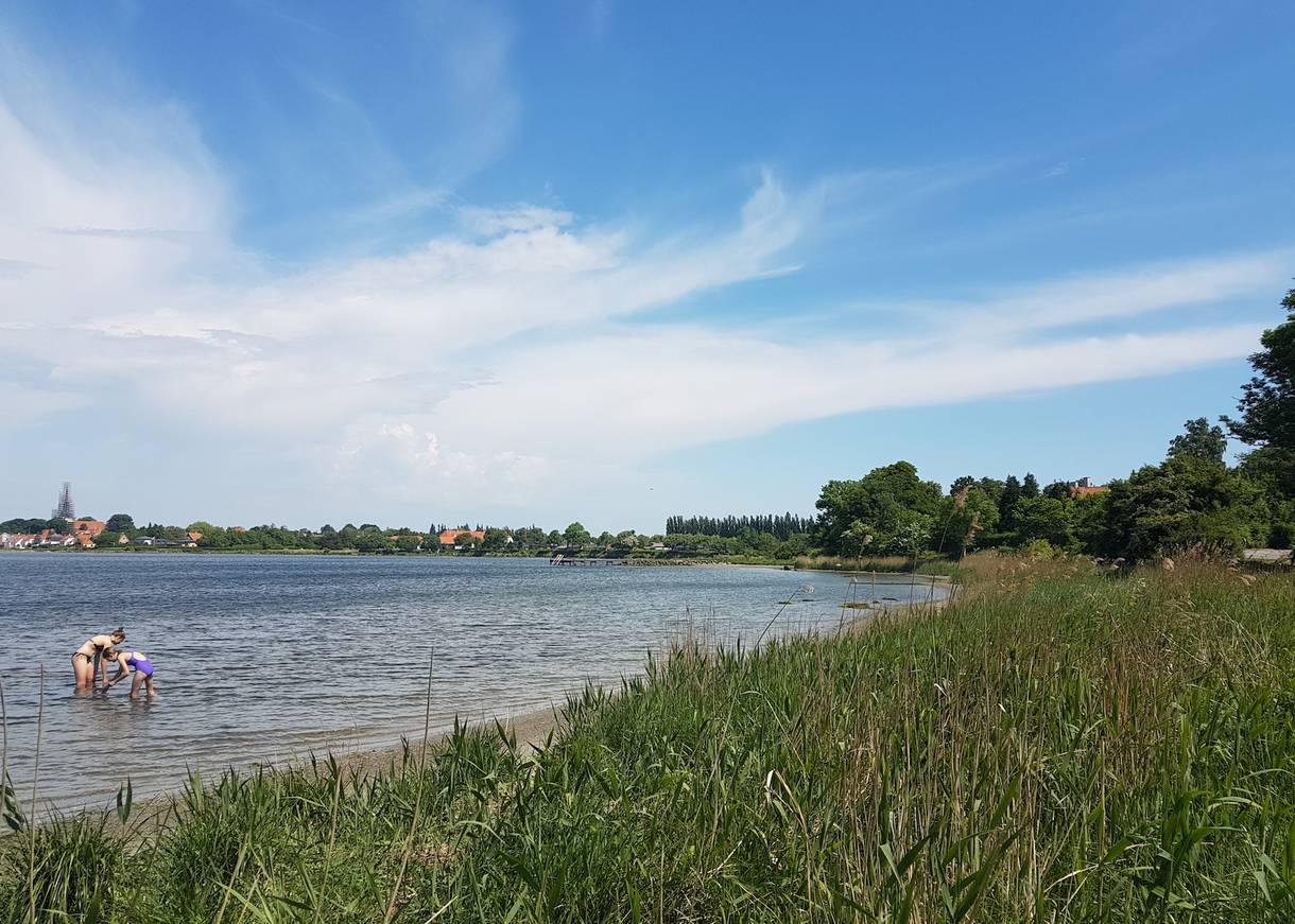 Badestelle mit der Silhouette einer Stadt im Hintergrund