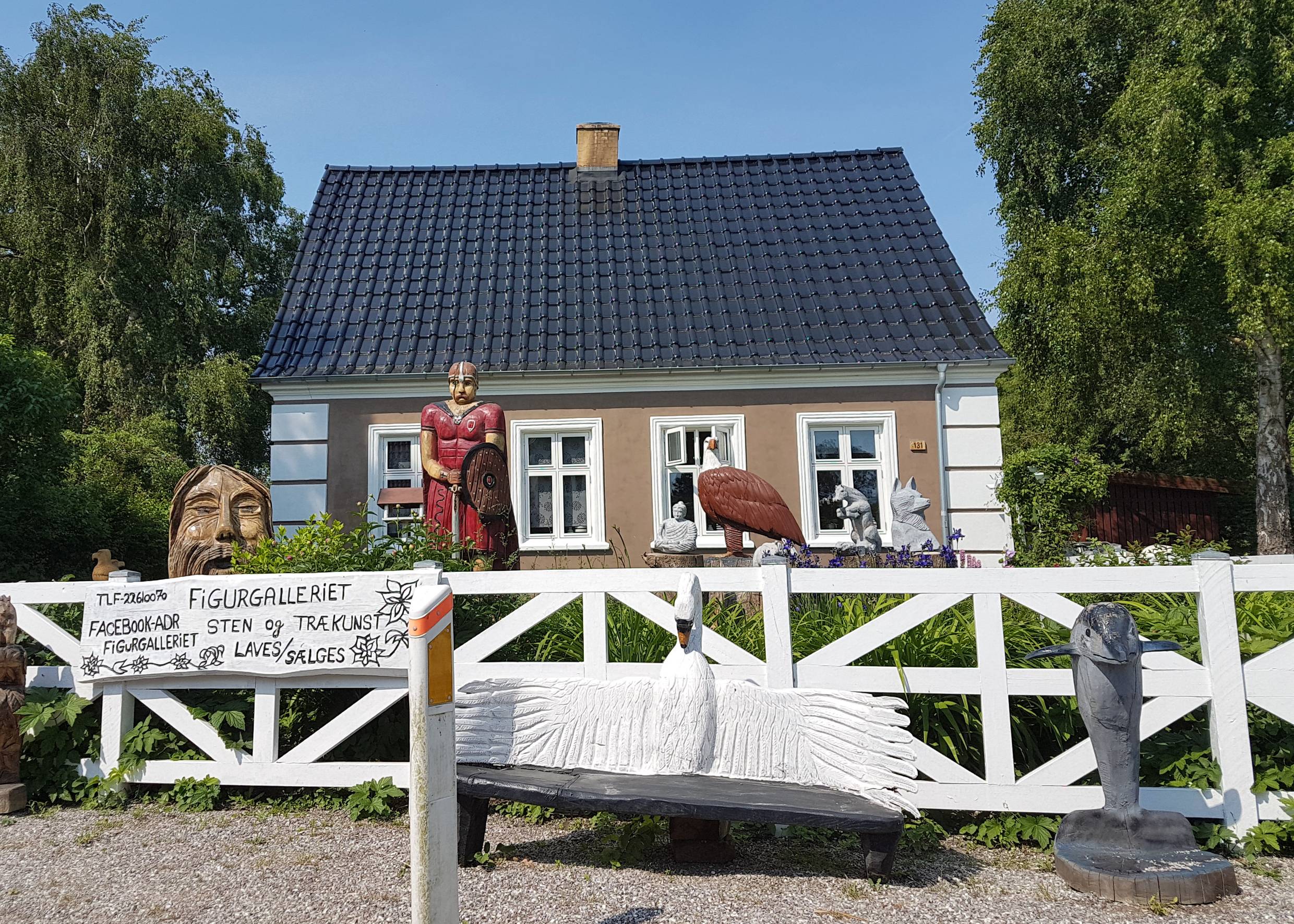 Haus mit geschnitzten Holzfiguren im Vorgarten