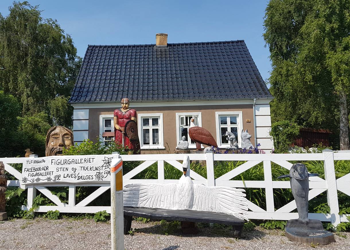 Haus mit geschnitzten Holzfiguren im Vorgarten