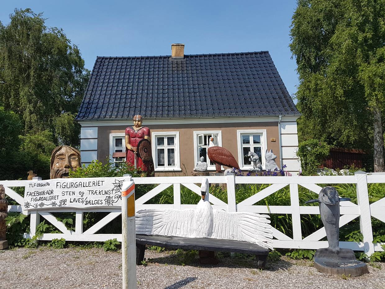 Haus mit geschnitzten Holzfiguren im Vorgarten