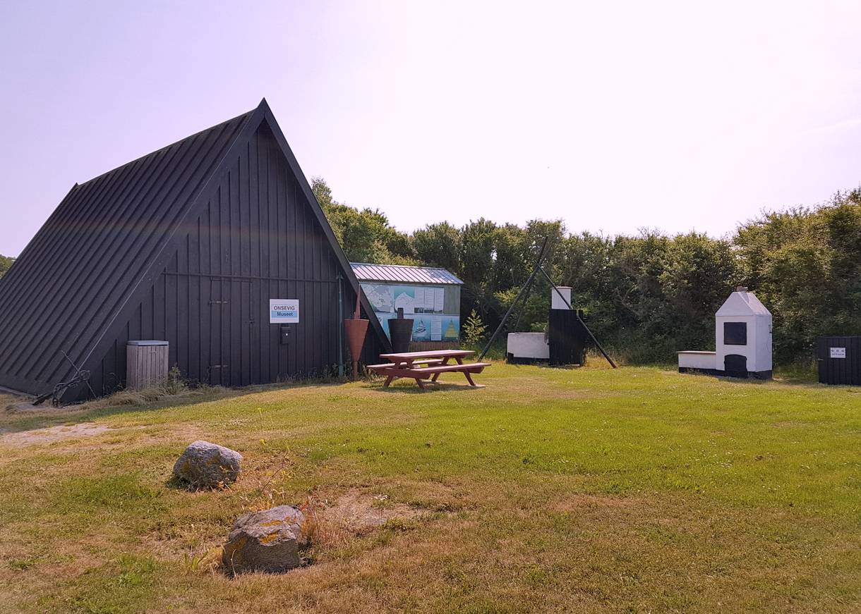Kleines Nurdachhaus mit Hinweisschild Museum
