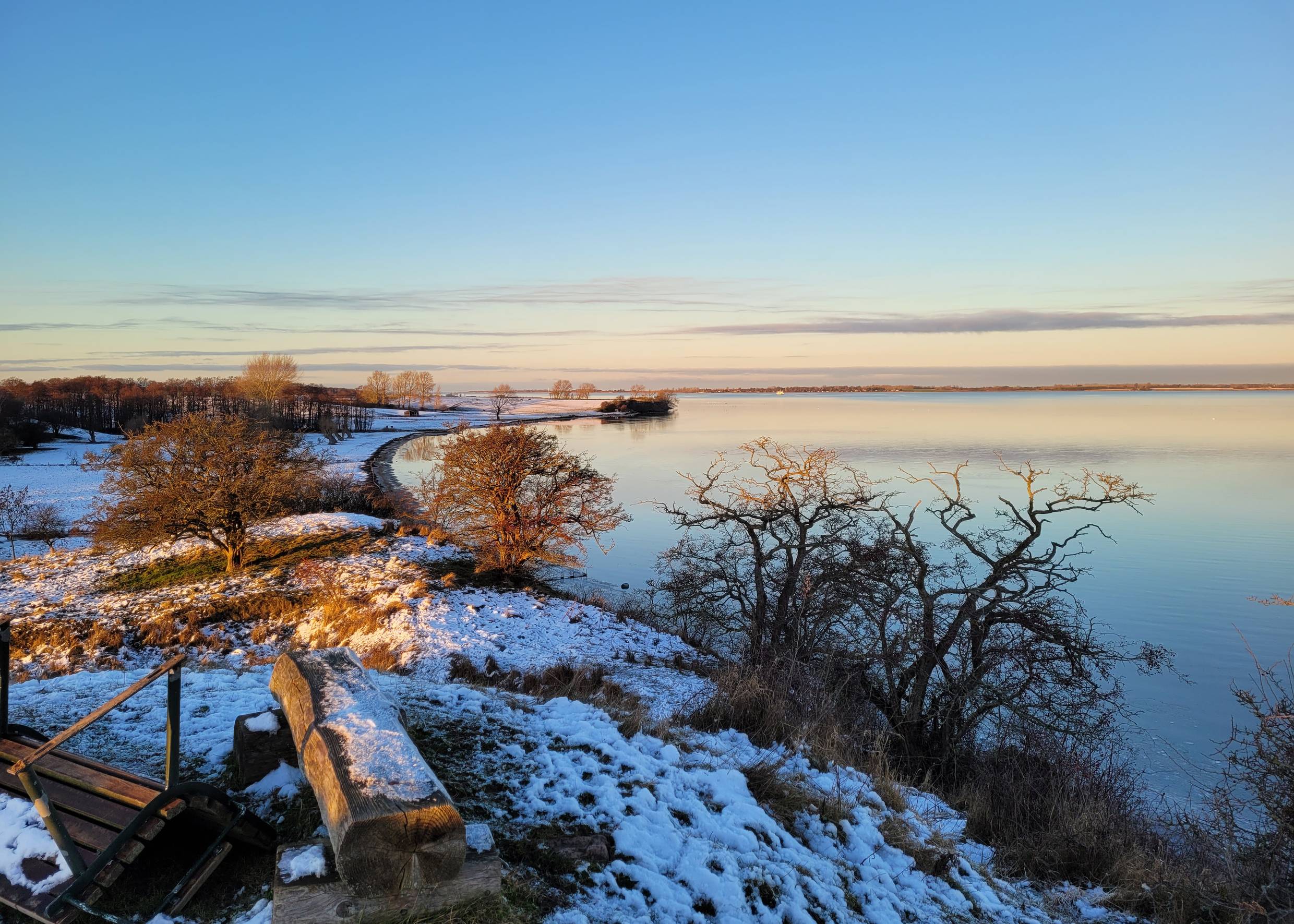 Blick auf die flache See an einem Winterabend, Schnee und rosa Himmel